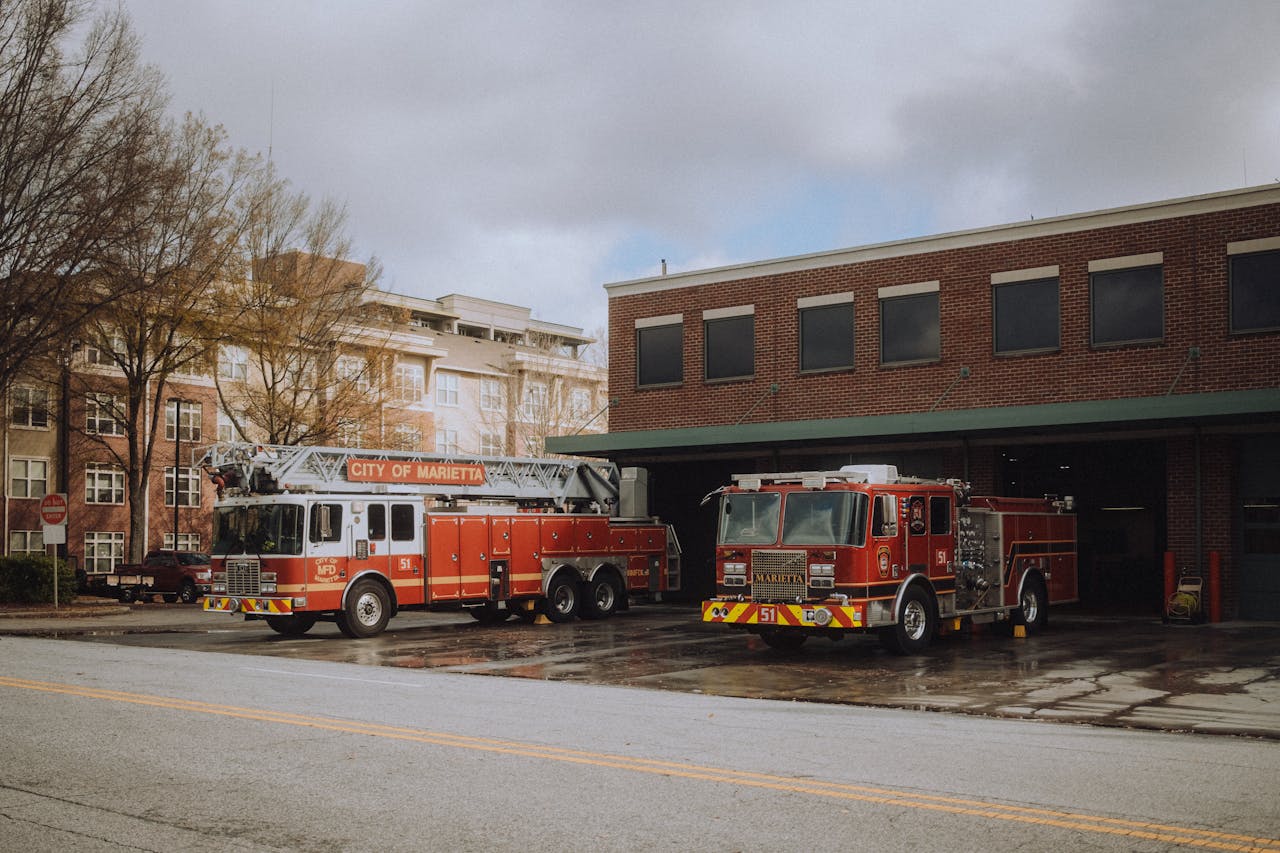 programs-01 Fire trucks parked outside a Marietta fire station on a cloudy day, ready for action.