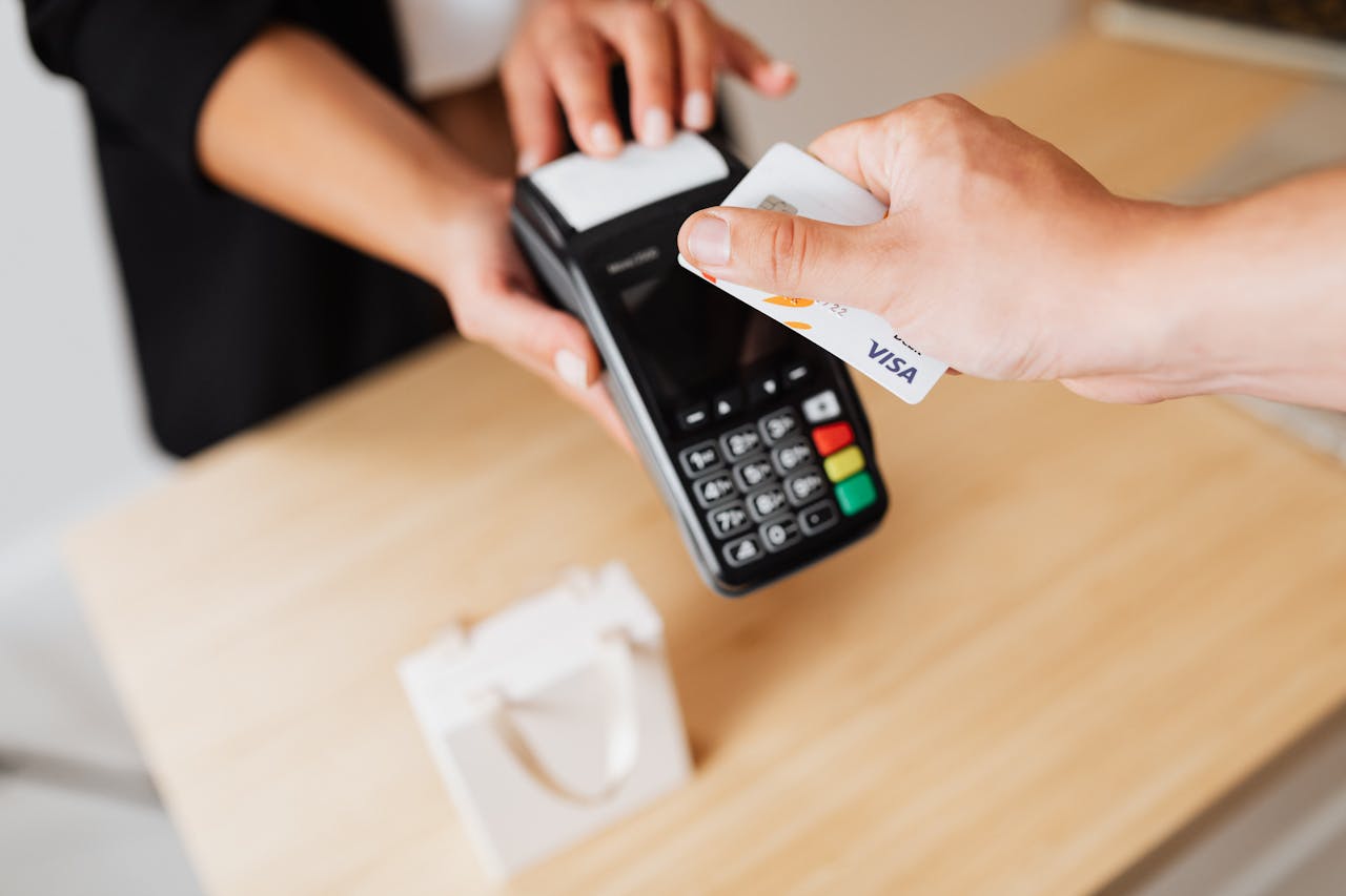 programs-01 Close-up of hands using a contactless payment terminal with a credit card indoors.