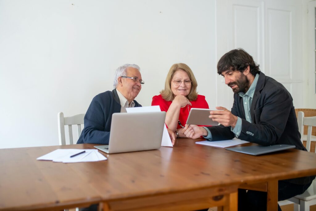 pexels photo 8439694 8439694 Two senior clients and a consultant discussing documents and using a tablet in a modern office.